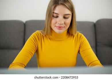 Beautiful blonde girl working on a computer at home with a smile