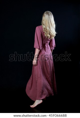 Beautiful blonde haired woman wearing a long flowing purple dress.   isolated on a black background.