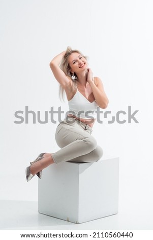 Beautiful blonde in jeans in the studio on a light background.