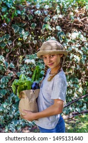 Beautiful Blonde Little Girl At Home Holding A Vegetable Brown Paper Bag With Groceries. No More Plastic Bags.