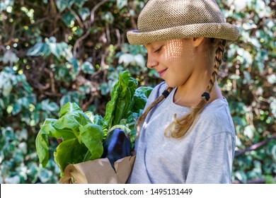 Beautiful Blonde Little Girl At Home Holding A Vegetable Brown Paper Bag With Groceries. No More Plastic Bags.