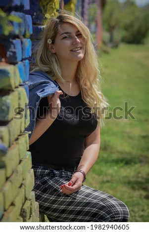 Beautiful blonde model posing in front of colorful wall on sunny day in eastern Serbia.