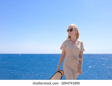 Beautiful blonde in sunglasses against the background of the blue sea and sky. Travel and tourism. Copy space.