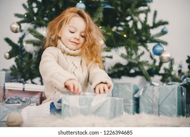 Beautiful Blonde Todler Girl Opening Presents Next To The Christmas Tree