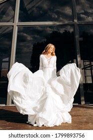 Beautiful Blonde Waving Wedding Dress On The Background Of A Modern Building