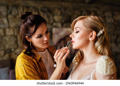 Beautiful blonde wedding bride with makeup and hairstyle. A professional makeup artist does the bride's makeup on the wedding day. Portrait of a young woman in the morning. - Powered by Shutterstock