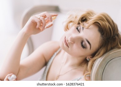 Beautiful blonde woman with a bottle of fragrant perfume in her hands. Close-up. Soft focus. Horizontal