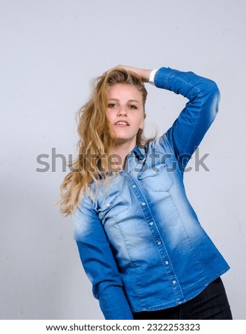 Beautiful blonde woman in a denim jacket posing on a white background in the studio. Space perspective.