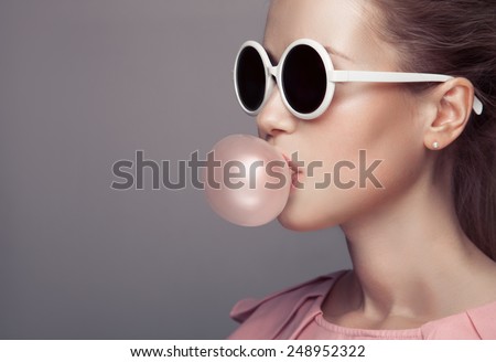 Beautiful blonde woman. Fashion portrait. Blowing bubble gum.