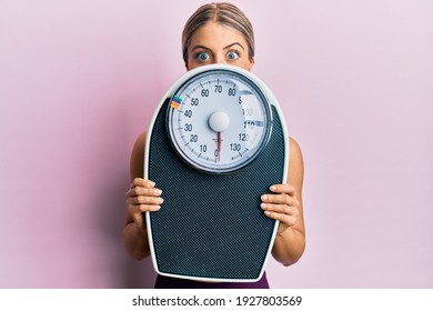 Beautiful Blonde Woman Holding Weight Machine To Balance Weight Loss Celebrating Crazy And Amazed For Success With Open Eyes Screaming Excited. 