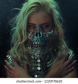 beautiful blonde woman with intense look wearing a silver mask with skull and metal pieces, halloween