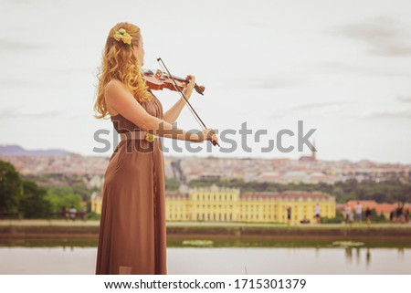 Beautiful blonde woman plays the violin outdoors. Violinist outdoors. 