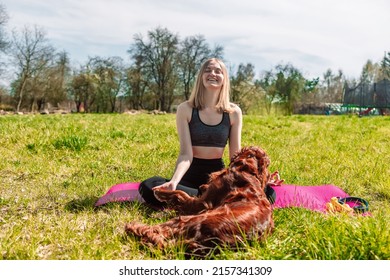 Beautiful blonde woman practice yoga lotus pose with Irish setter dog dog enjoy and relax with yoga in nature at park