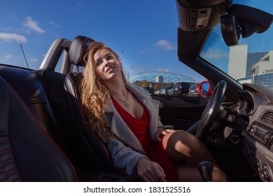 Beautiful Blonde Woman In A Red Dress Posing In A Red Car 