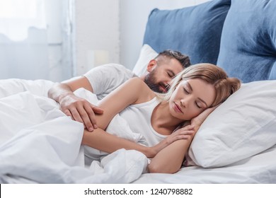 beautiful blonde woman sleeping in bed with boyfriend in morning 