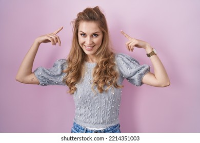 Beautiful Blonde Woman Standing Over Pink Background Smiling Pointing To Head With Both Hands Finger, Great Idea Or Thought, Good Memory 