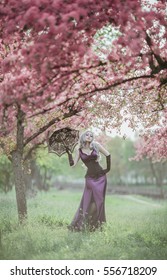 Beautiful blonde woman walking in spring garden under blooming trees. Spring gothic fashion. Cute flower scene - Shutterstock ID 556718209
