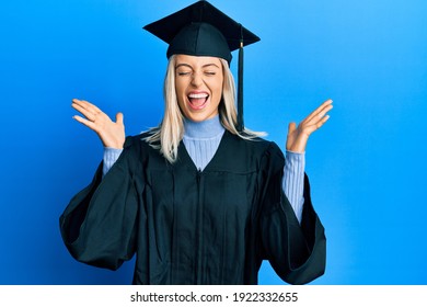 Beautiful blonde woman wearing graduation cap and ceremony robe celebrating mad and crazy for success with arms raised and closed eyes screaming excited. winner concept 