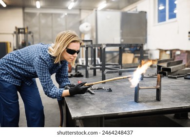 Beautiful blonde woman works as a welder in workshop, operating welding machine, wearing safety goggles for eye protection. - Powered by Shutterstock