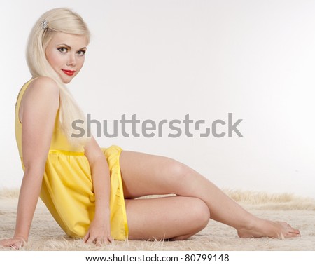 beautiful blonde in yellow dress posing on a white