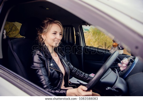 beautiful blonde a young girl, the driver behind the\
wheel of a car