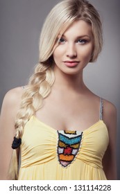 Beautiful Blonde Young Woman With Braid Hairdo In Yellow Dress, Looking At Camera