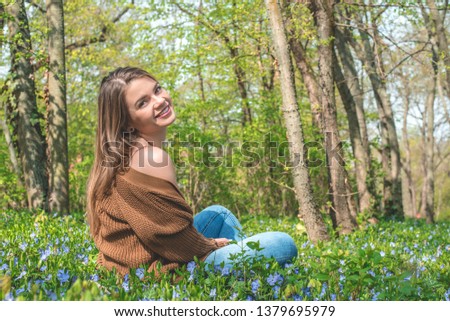 Beautiful blonde young woman is having fun in the park in spring