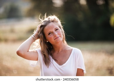 Beautiful Blonde Young Woman Pulling Hair Back Looking At Camera