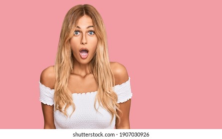 Beautiful blonde young woman wearing casual white tshirt afraid and shocked with surprise expression, fear and excited face. 