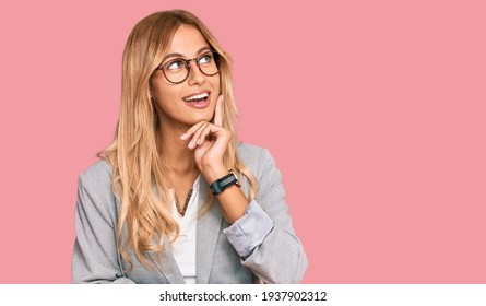 Beautiful Blonde Young Woman Wearing Business Clothes With Hand On Chin Thinking About Question, Pensive Expression. Smiling And Thoughtful Face. Doubt Concept. 