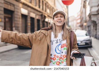 Beautiful Blonde Young Woman Wearing Brown Trench Coat And White Cap Looking At The Camera Smiling With Open Arms For Hug, Cheerful Expression Embracing Happiness, Good Meeting Of Friends Or Family.