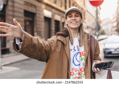 Beautiful Blonde Young Woman Wearing Brown Trench Coat And White Cap Looking At The Camera Smiling With Open Arms For Hug, Cheerful Expression Embracing Happiness, Good Meeting Of Friends Or Family.