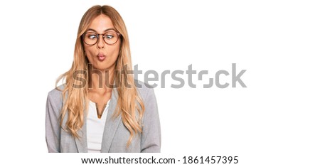 Beautiful blonde young woman wearing business clothes making fish face with lips, crazy and comical gesture. funny expression. 