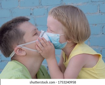 Beautiful Blond-haired Child In Protective Medical Mask Hugs And Kisses His Mother. Bald Extravagant Woman In Green Coat And Quarantine Medical Mask, Blue Gloves