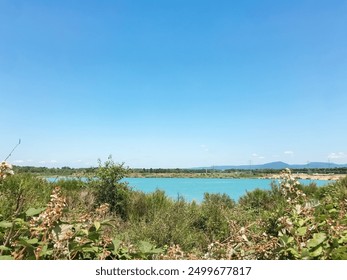 A beautiful blue lake with a clear sky above it, set in a granite quarry. Perfect for showcasing serene natural beauty and rugged, industrial landscapes. - Powered by Shutterstock