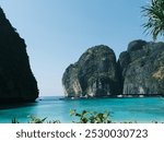 A beautiful blue ocean with a mountain range in the background. The mountains are covered in green trees and the water is calm