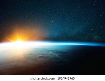 Beautiful blue planet earth in outer space on background of stars and milky way with sunrise. Amazing yellow sunset from space. World with sunlight