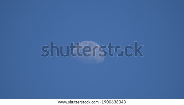 Beautiful blue sky with daytime moon, moon view from the\
mountain, natural satellite of earth, cloudless blue sky with clear\
moon in the sky, skymoon, bluemoon, moonblue, blue sky with moon \
