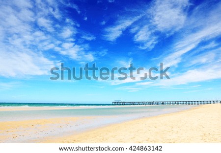 Beautiful blue sky over wide sandy beach with jetty pier in background. Taken at Henley Beach, South Australia.