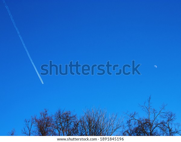 The\
beautiful blue sky with a plane and the moon on it on a sunny day.\
Winter or spring natural background. Selective\
focus.