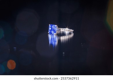 Beautiful blue stoned ring on a reflective surface and black background - Powered by Shutterstock