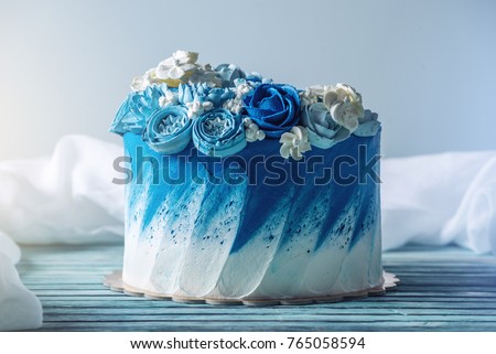 Beautiful blue wedding cake decorated with white flowers of cream with a place for a label. The concept of Holiday desserts for a birthday