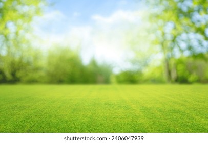 Beautiful blurred background image of spring nature with a neatly trimmed lawn surrounded by trees against a blue sky with clouds on a bright sunny day. Arkivfotografi