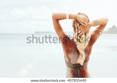 Beautiful bohemian styled and tanned girl at the beach in sunlight