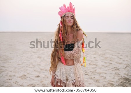 Beautiful boho styled girl with long hair on the sunset beach