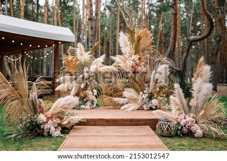Beautiful boho wedding arch with green plants on green pine forrest