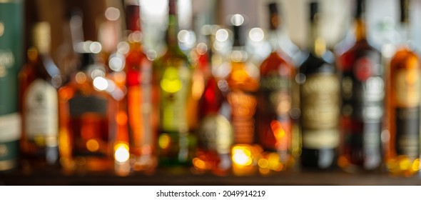 Beautiful bokeh from a row of alcoholic bottles in backlight. Panoramic shot.