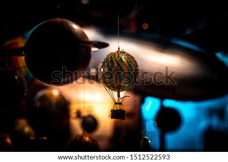Beautiful bokeh of a small hot air balloon toy hanging with planets and airships in the background. Concept of nostalgic memories of astonishment for science.