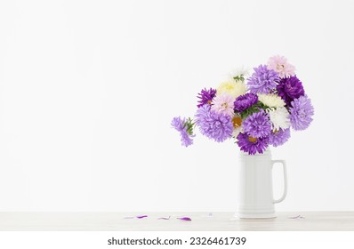 beautiful bouquet of asters in white jug on background white wall