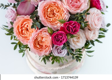 beautiful bouquet in a box on a white table, top view, close-up with blurred background, peony rose, pink rose, purple rose, greens